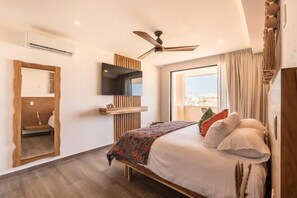 Ein modernes Schlafzimmer mit Bett, Deckenventilator, einem angebrachten Fernseher und einem großen Fenster.