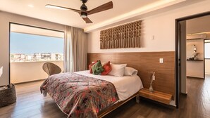 Een moderne hotelkamer met een groot bed, een plafondventilator, uitzicht door een balkon en een houten hoofdbord.