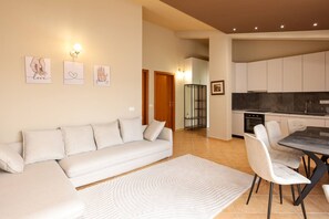 Ein modernes Wohnzimmer mit Sofa, Esstisch, Stühlen und einer Küchenzeile.