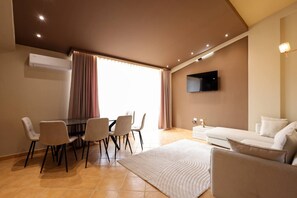 Ein modernes Wohnzimmer mit Essbereich, einem Flachbildfernseher und einer Couch.
