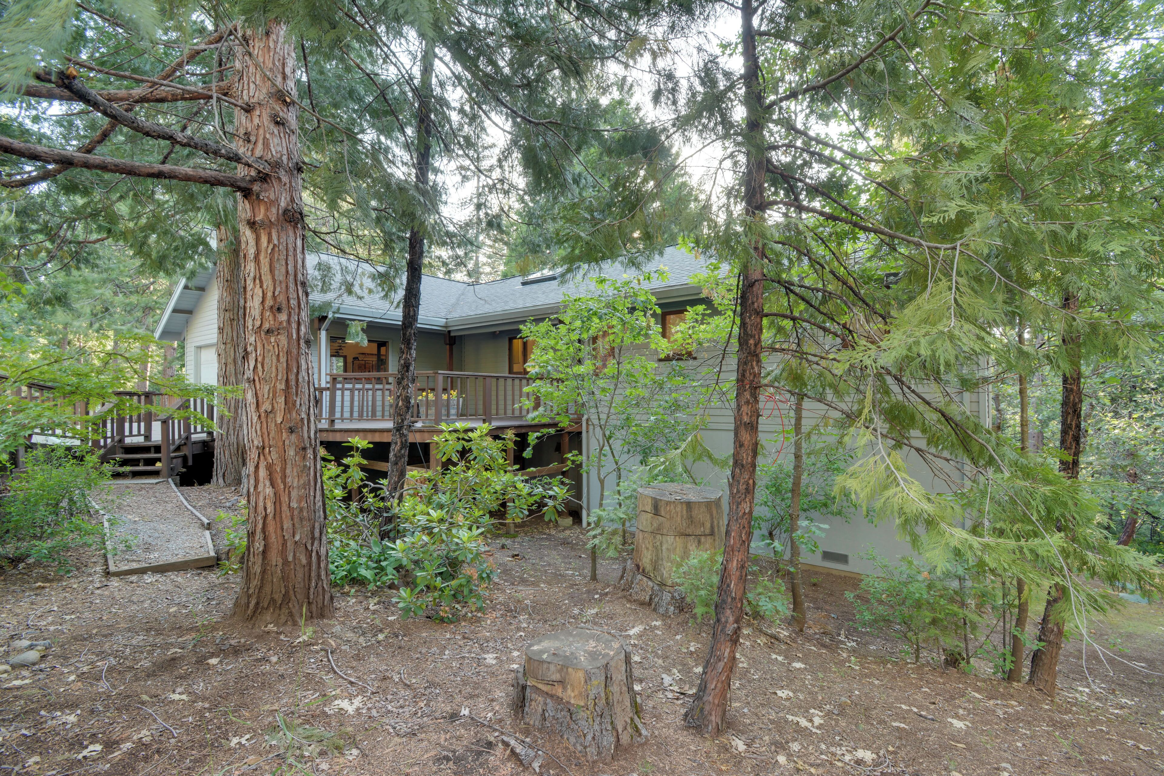 A house surrounded by trees with a deck and a covered porch.