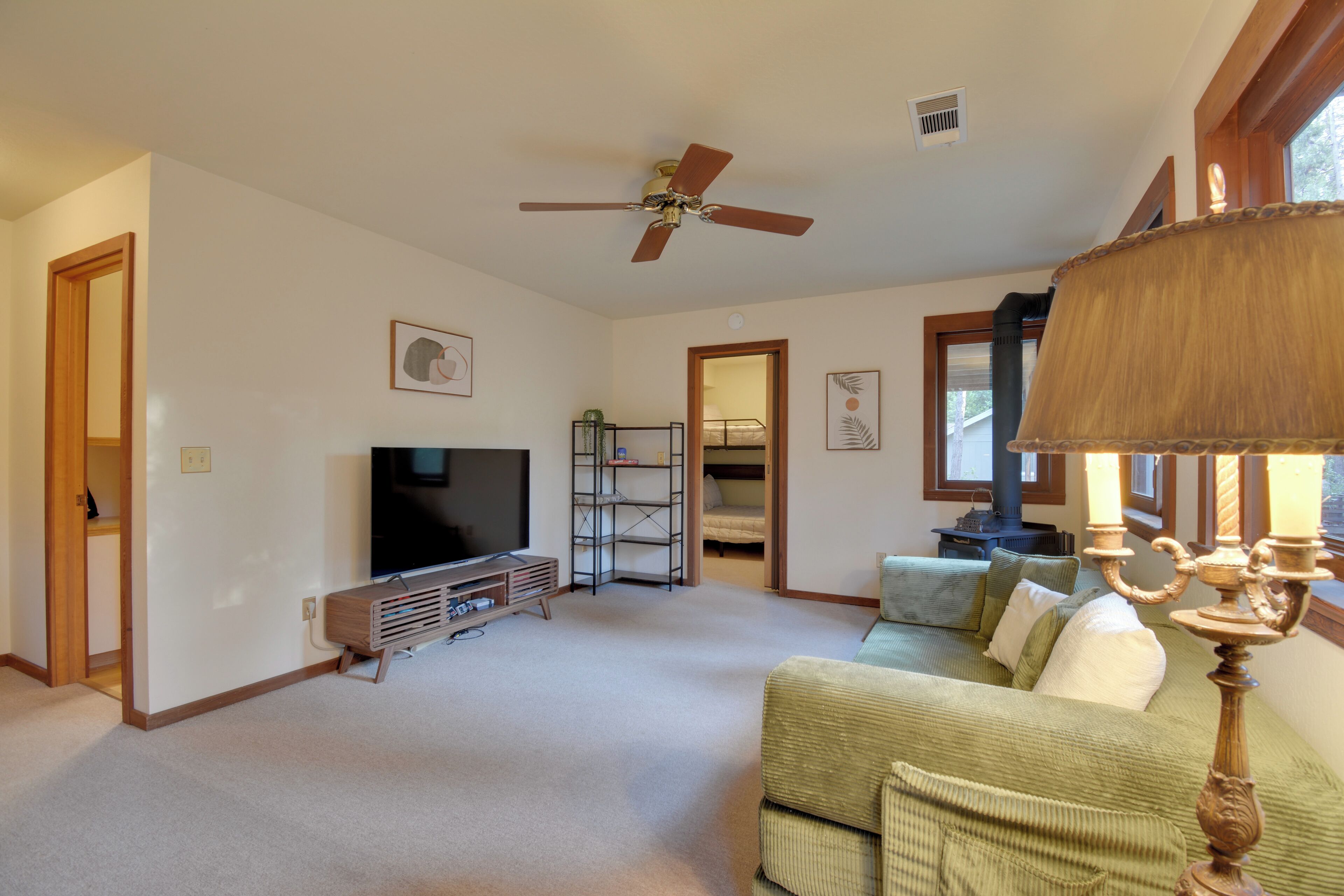 Ein Wohnzimmer mit Fernseher, Deckenventilator, Bücherregal, Sofa und Lampe.