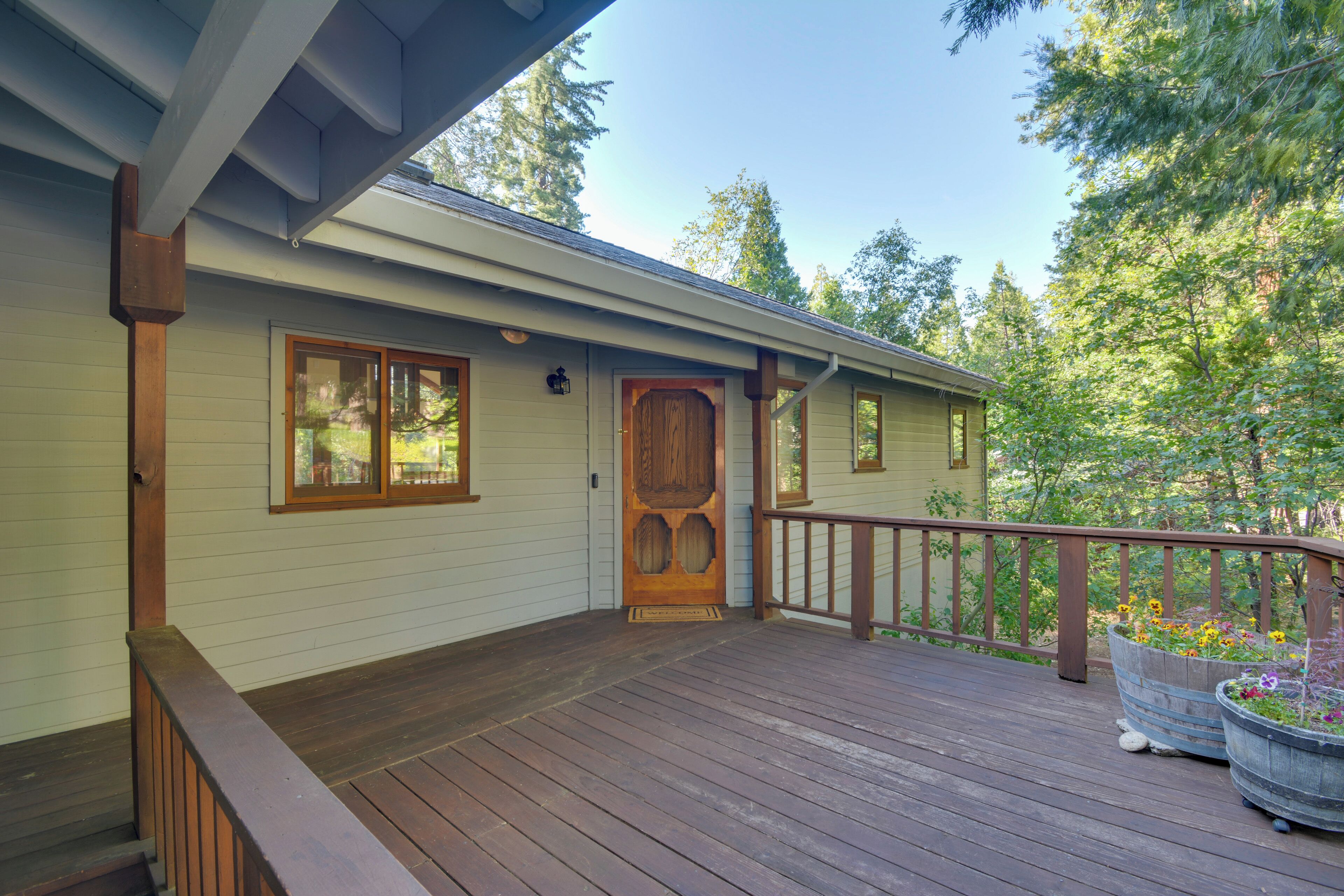 A wooden deck with a railing, a door, and a window.