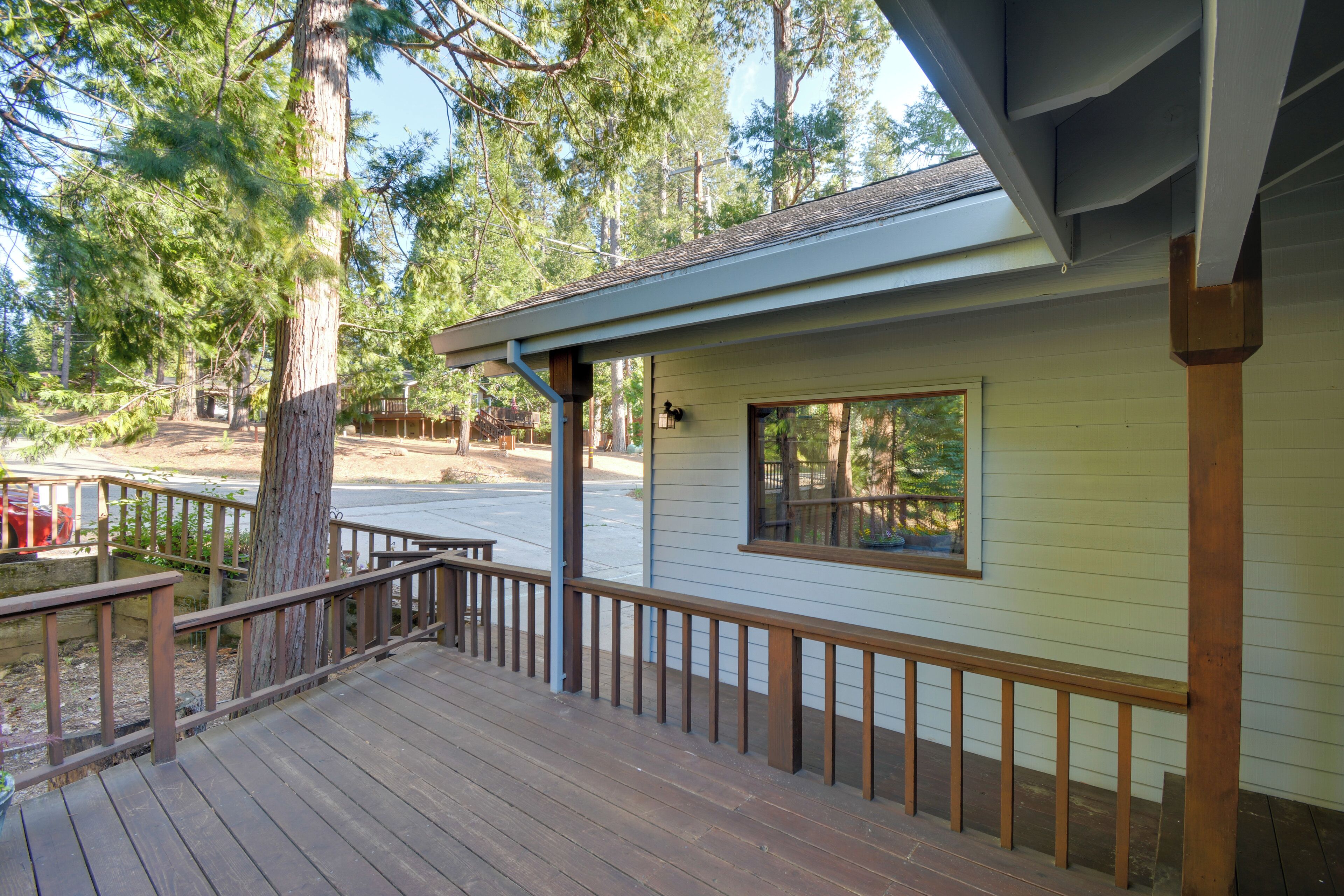 A wooden deck with a railing, a small window, and a tree in the background.