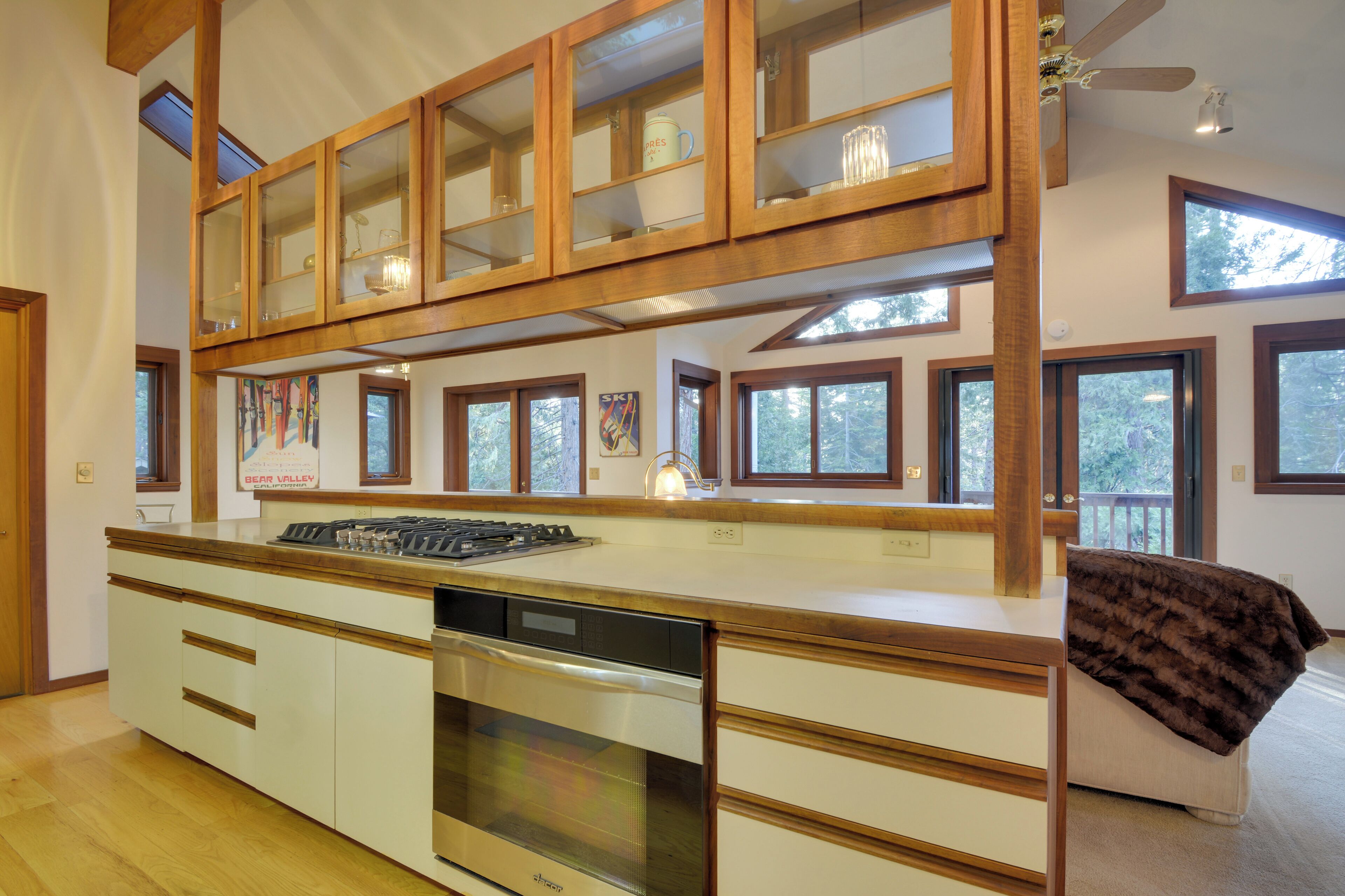 Une cuisine équipée d’une cuisinière, d’un four et d’un lave-vaisselle, avec des meubles en bois et de grandes fenêtres.