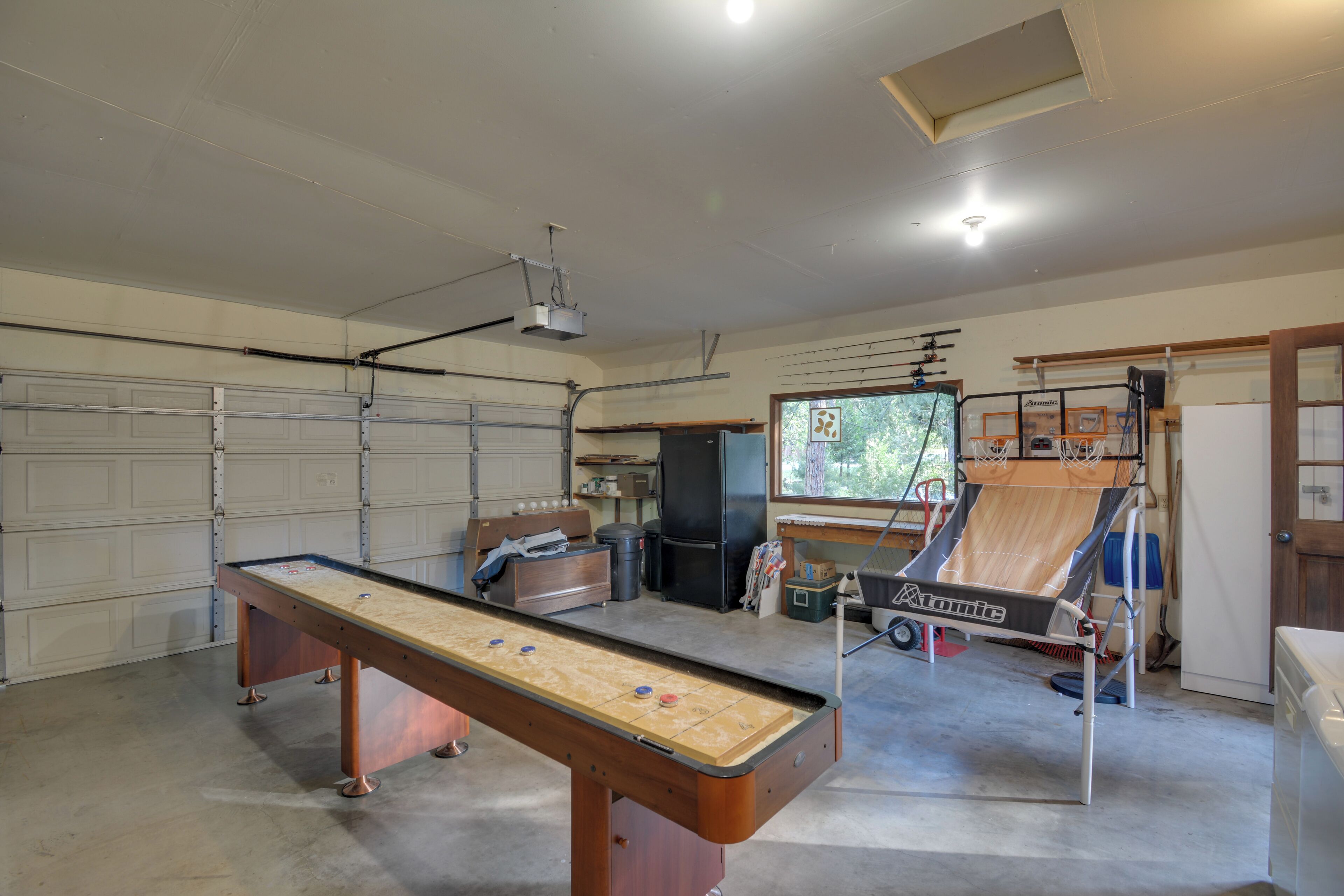 A garage with a shuffleboard table, a pool table, and a billiards table.