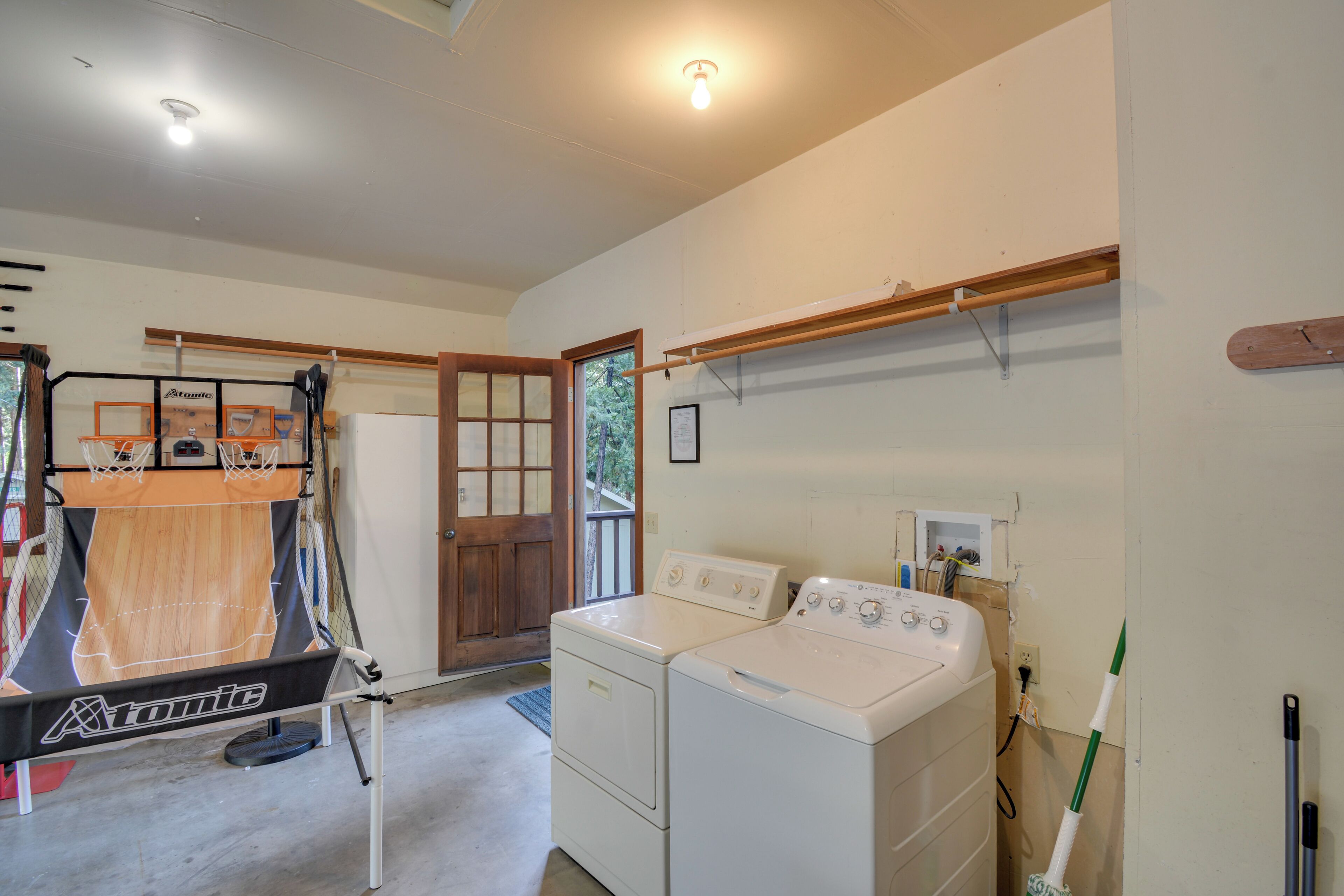 A laundry room with a washing machine, dryer, and a basketball hoop.
