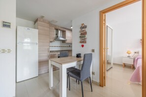 Eine kleine Küche mit Kühlschrank, Holzschränken, einem Esstisch mit zwei Stühlen und einer Wand mit motivierenden Sprüchen.