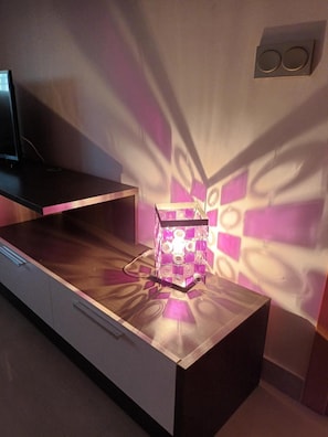 Ein moderner Raum mit Schreibtisch, einer Zierlampe und einem Wandlautsprecher.