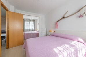 Ein Schlafzimmer mit einem Bett, einem Kleiderschrank, einem Schreibtisch und einem Spiegel.