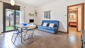 Un salon moderne avec un canapé bleu, une table à manger avec des chaises, un téléviseur et un balcon avec vue.
