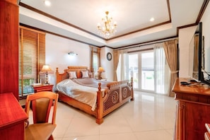 A bedroom with a large bed, wooden furniture, a chandelier, and a view through the window. - Villa Nautica Pattaya - 4BR Pool Villa With Private Boathouse (Bang Lamung)