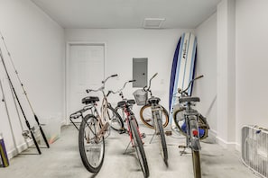 A room with bicycles, a surfboard, and fishing rods.