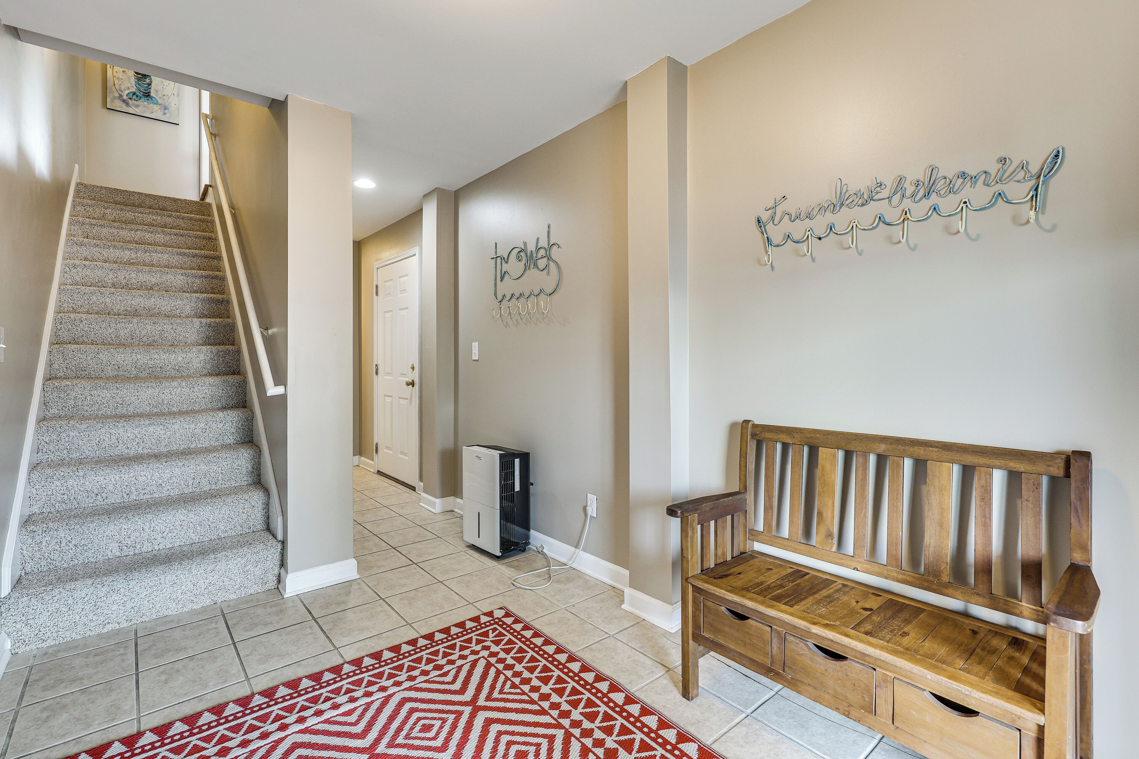 A staircase, a wooden bench, a wall-mounted sign, and a hallway with a door.