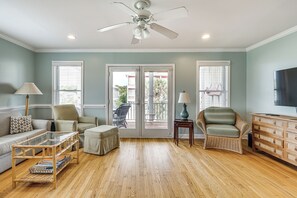 A living room with a glass coffee table, a sofa, a chair, a television, and a wooden cabinet.
