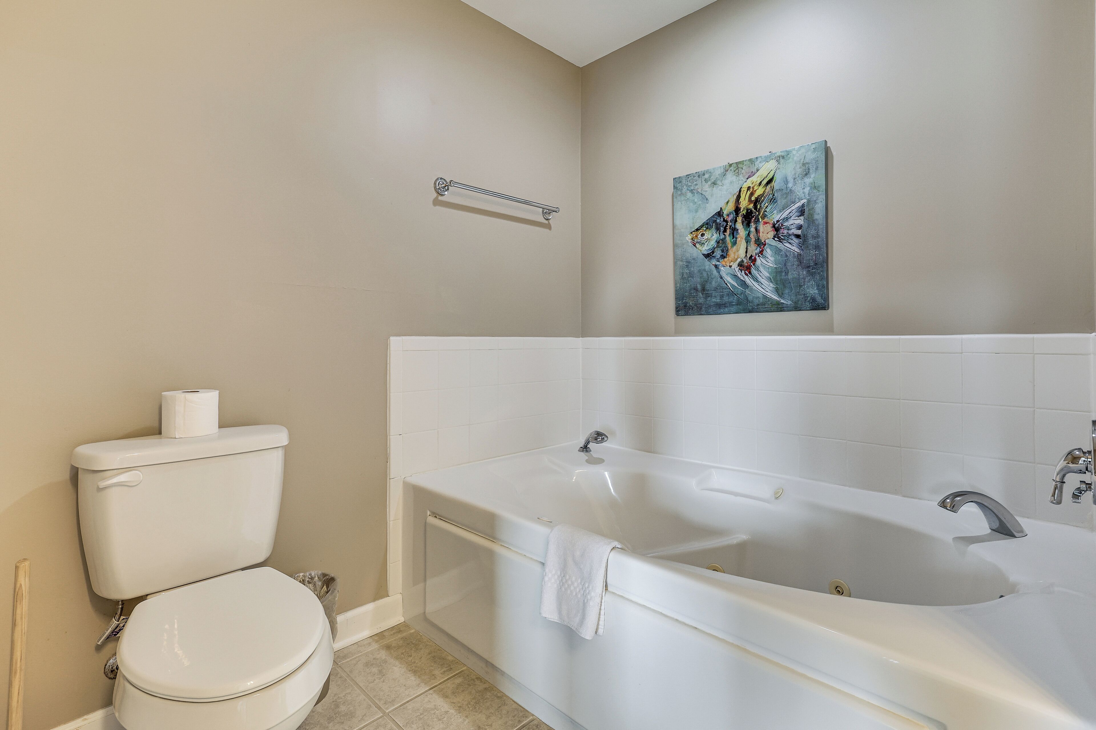 A bathroom with a toilet, bathtub, and a towel rack.