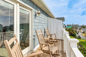 A balcony with wooden chairs and a glass door.