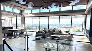 Amplia sala de estar con un sofá modular grande, una mesa de centro de vidrio y un comedor con mesa y sillas.