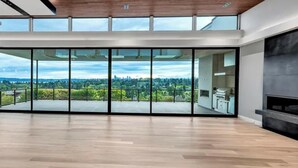 Una habitación amplia con ventanas grandes, suelo de madera y vistas a un paisaje verde.