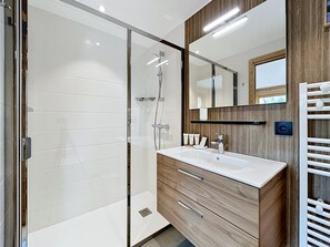 Un bagno moderno con cabina doccia in vetro, un mobile bagno in legno con lavandino e uno specchio grande.