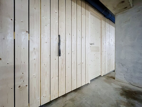 Una stanza con un armadio in legno, pavimento in cemento e un tubo blu che corre lungo il soffitto.