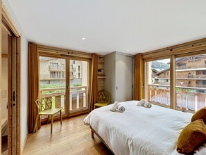 Camera da letto con un letto grande, una sedia e vista su un edificio con balconi.