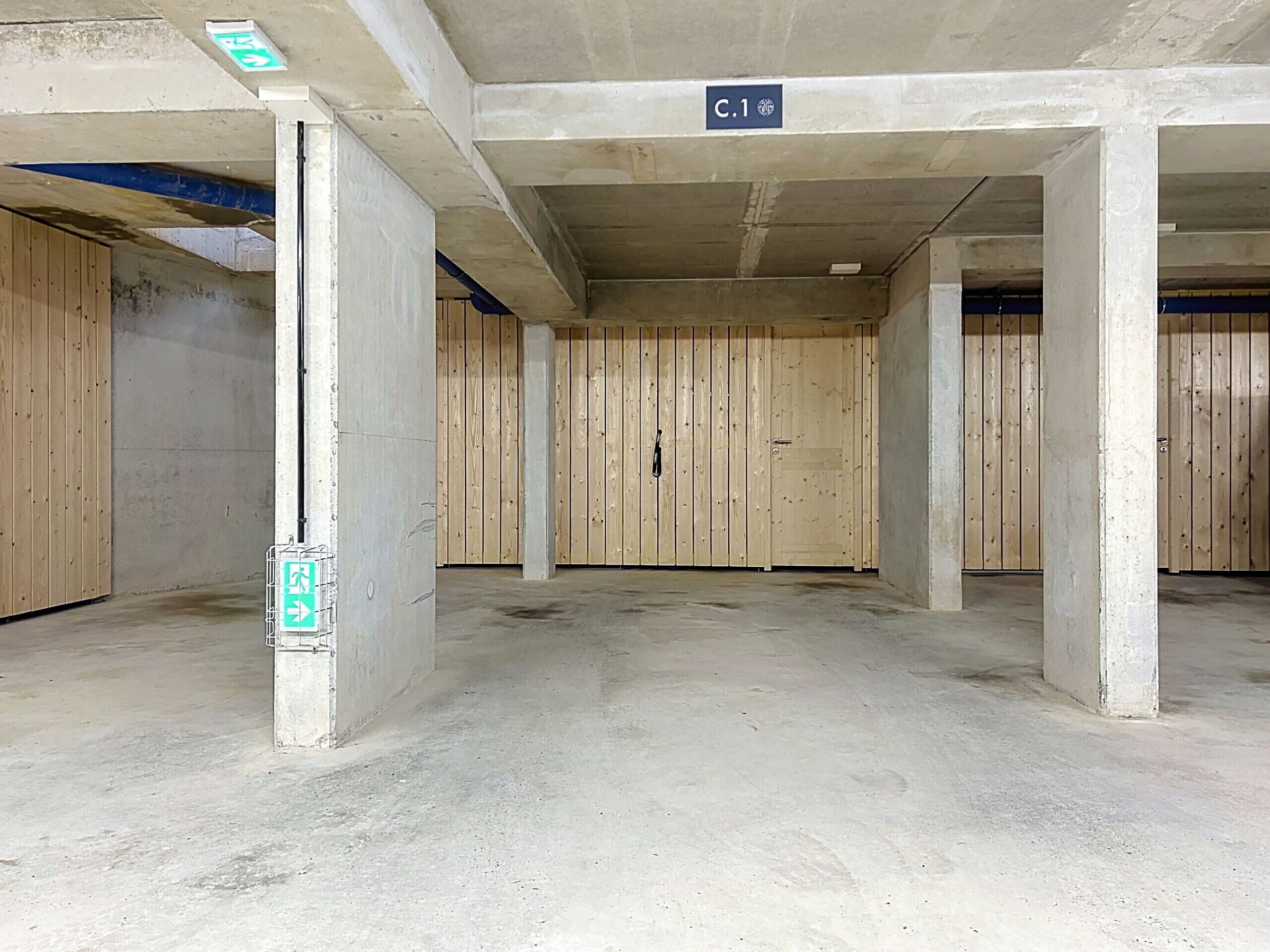 A parking garage with concrete pillars, wooden walls, and a sign indicating 'C.1'.