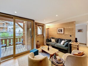 Ein modernes Wohnzimmer mit Holzboden, einer Couch, einem Couchtisch und einer Glastür zum Außenbereich.