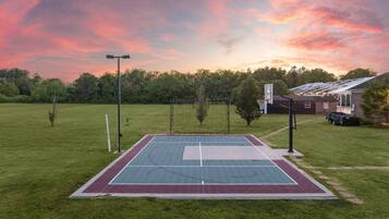 An outdoor basketball court with a net, a goal, and a fence.