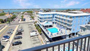 Ein mehrstöckiges Hotel mit Pool, Parkplatz und Blick auf das Meer.