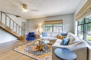 A living room with a staircase, a sofa, a coffee table, and a lamp. - Cozy Eclectic Cabin w/ Lake Views & Shared Dock! (Eclectic)