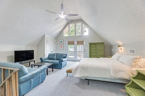 A bedroom with a bed, a TV, a sofa, and a ceiling fan. - Cozy Eclectic Cabin w/ Lake Views & Shared Dock! (Eclectic)