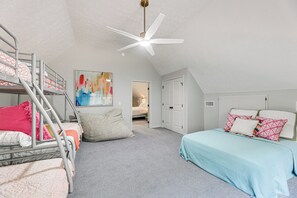 A bedroom with bunk beds, a ceiling fan, a painting, and a door leading to another room. - Cozy Eclectic Cabin w/ Lake Views & Shared Dock! (Eclectic)