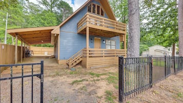 A cabin with a covered porch, a wooden deck, and a fenced yard.