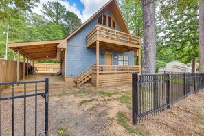 A cabin with a covered porch, a wooden deck, and a fenced yard. - Cozy Eclectic Cabin w/ Lake Views & Shared Dock! (Eclectic)