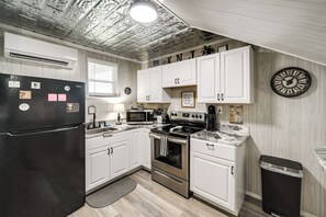 Eine Küche mit weißen Schränken, einem schwarzen Kühlschrank, Edelstahlgeräten und einer Holzbalkendecke.