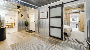 A modern interior with a wooden floor, a sliding barn door, and a visible dressing room. - Fredericksburg Barn w/ Balcony: Sip, Soak + Hike (Fredericksburg)