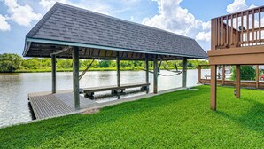A covered dock extending over water with a grassy area in front. - Waterfront Studio w/ Dock, 8 Mi to Kemah Boardwalk (Dickinson)