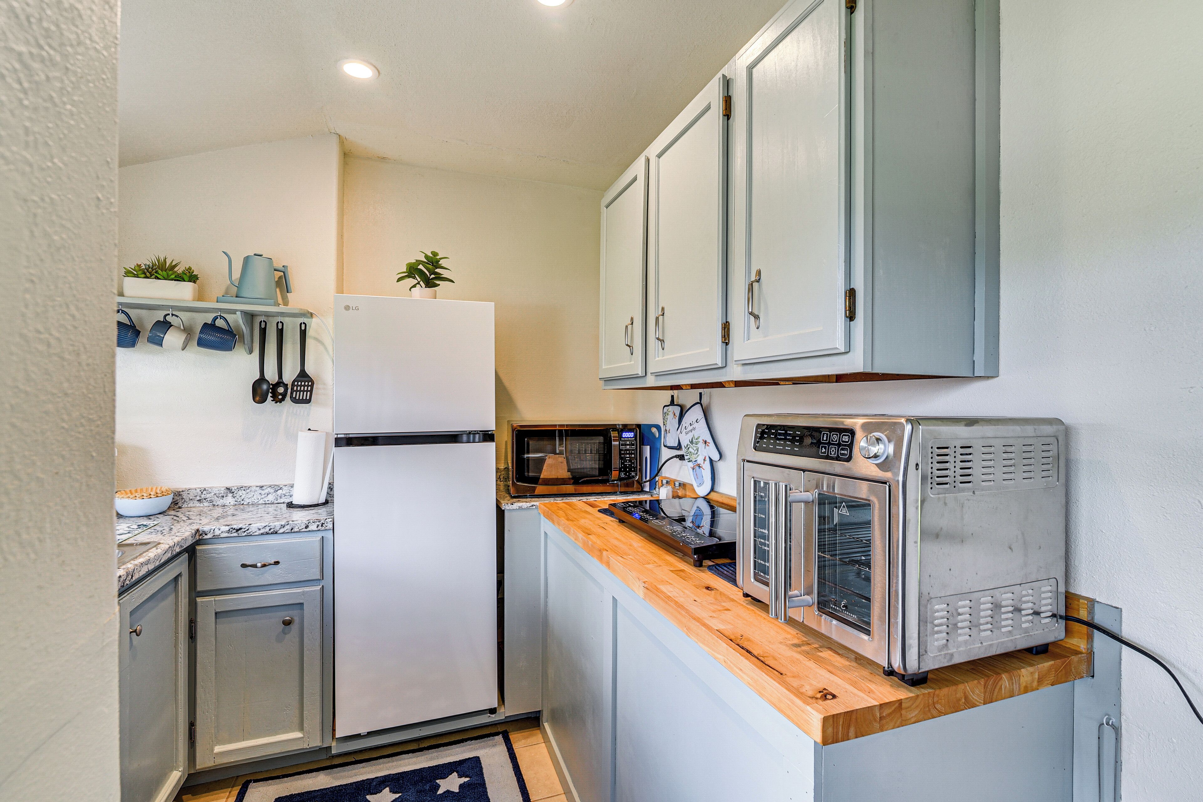 A compact kitchen with a refrigerator, microwave, toaster oven, and wooden countertop.