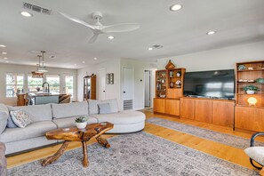 A modern living room with a sofa, coffee table, TV, wooden cabinets, and a ceiling fan. - Elegant Waterfront Retreat w/ Dock in Dickinson (Dickinson)