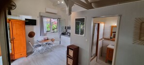A compact kitchen with a dining area, a wardrobe, and a shower area. - Le Cardinal : Independent studio, sea view, saltwater swimming pool, wooded garden (Saint-Leu)