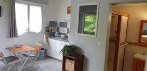 A compact kitchen with a dining area, a window with a view of greenery, and a shower area. - Le Cardinal : Independent studio, sea view, saltwater swimming pool, wooded garden (Saint-Leu)