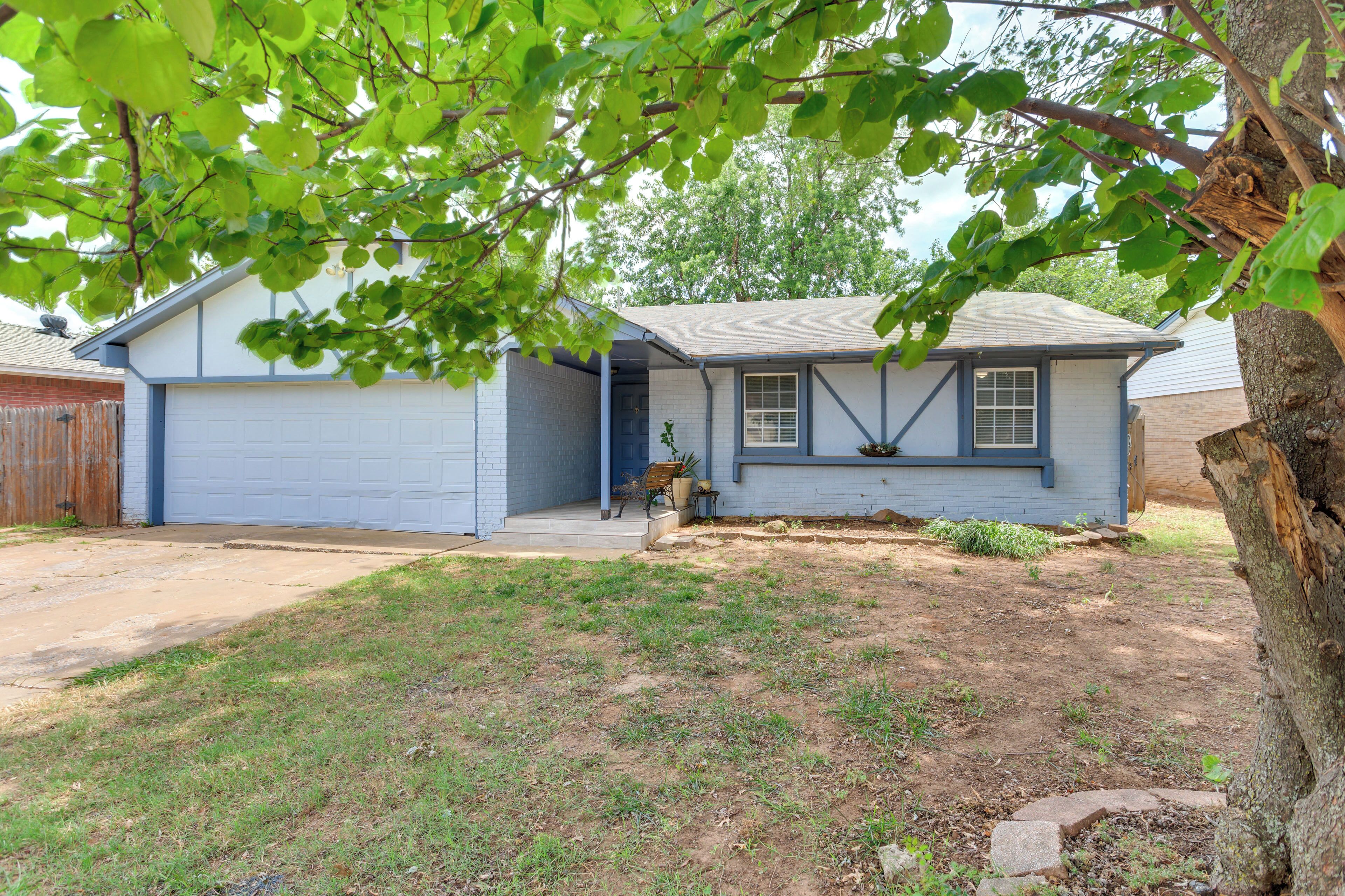 A single-story house with a garage, a front porch, and a tree in the foreground.