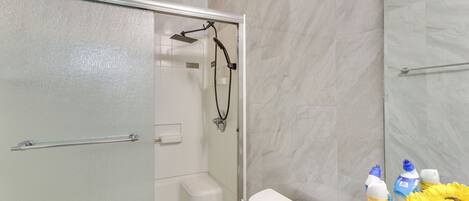 A modern bathroom with a glass-enclosed shower, a white toilet, and a marble wall.