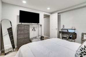 A bedroom with a bed, a desk, a chair, a TV, and a wardrobe. - Work & Play in Baldwin! Cozy Apartment w/ Grill (Baldwin)