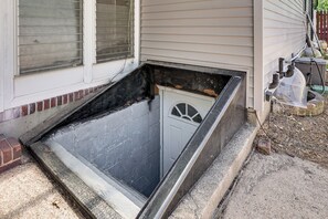 Un espacio reducido y cerrado con una puerta, una ventana con persianas y un pequeño escalón de acceso.