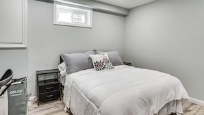A bedroom with a bed, nightstand, and a small window.