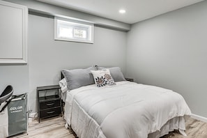 A bedroom with a bed, nightstand, and a small window. - Work & Play in Baldwin! Cozy Apartment w/ Grill (Baldwin)