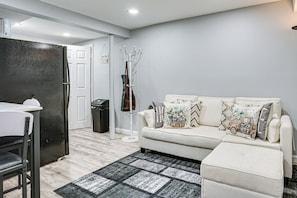A living room with a sofa, a coffee table, a dining table, and a kitchen area. - Work & Play in Baldwin! Cozy Apartment w/ Grill (Baldwin)