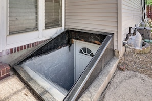 A narrow, enclosed space with a door, a window with blinds, and a small step leading up to it. - Work & Play in Baldwin! Cozy Apartment w/ Grill (Baldwin)